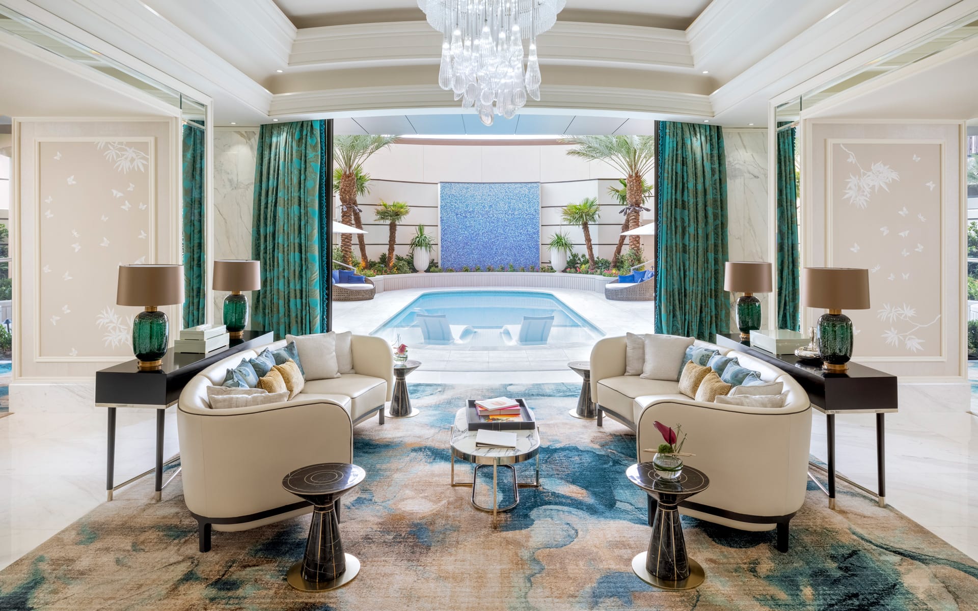 Luxurious living room with elegant sofas, stylish decor, and view of a pool through large glass doors, featuring green accents.