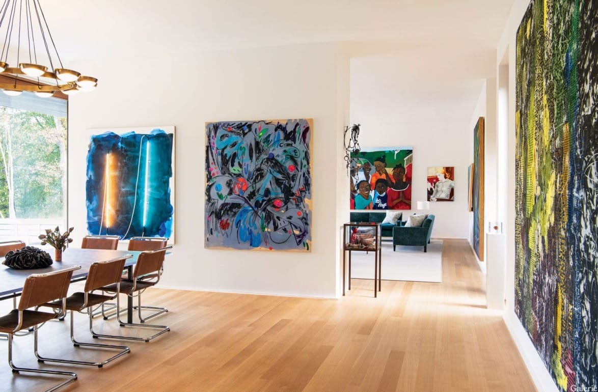 Modern dining room with wooden floors, large paintings on the walls, a dining table with chairs, and floor-to-ceiling windows.