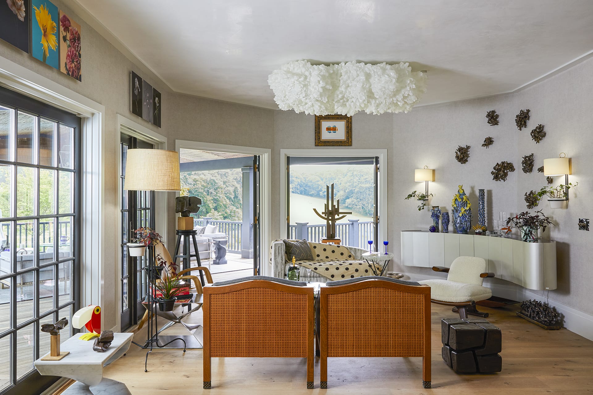 Spacious contemporary living room with large windows, modern decor, and balcony overlooking scenic mountain view.