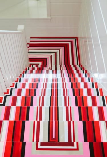 Colorful, abstract staircase with bold red, pink, black, and white geometric patterns, viewed from the top.
