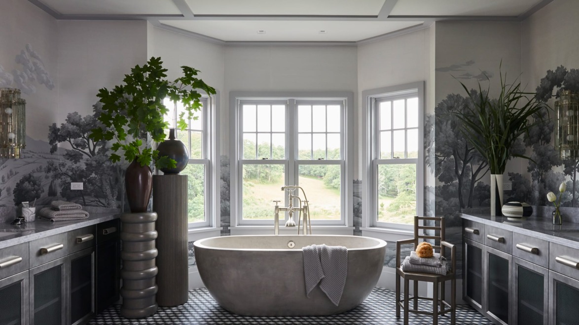 Luxurious bathroom with freestanding tub, large windows, patterned floor, and elegant plants.