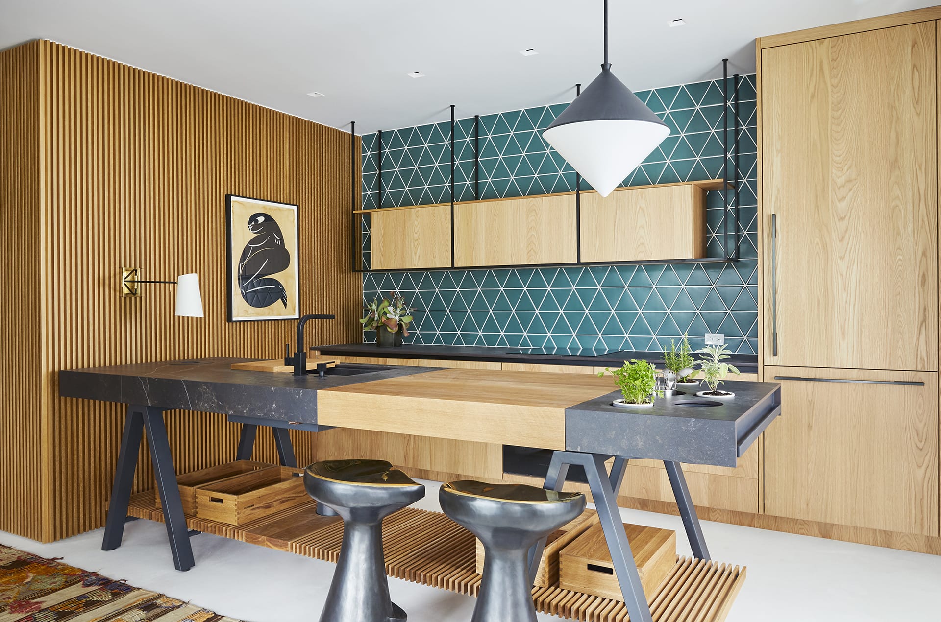 Modern kitchen with wooden cabinets, teal geometric backsplash, black countertops, and minimalist decor.