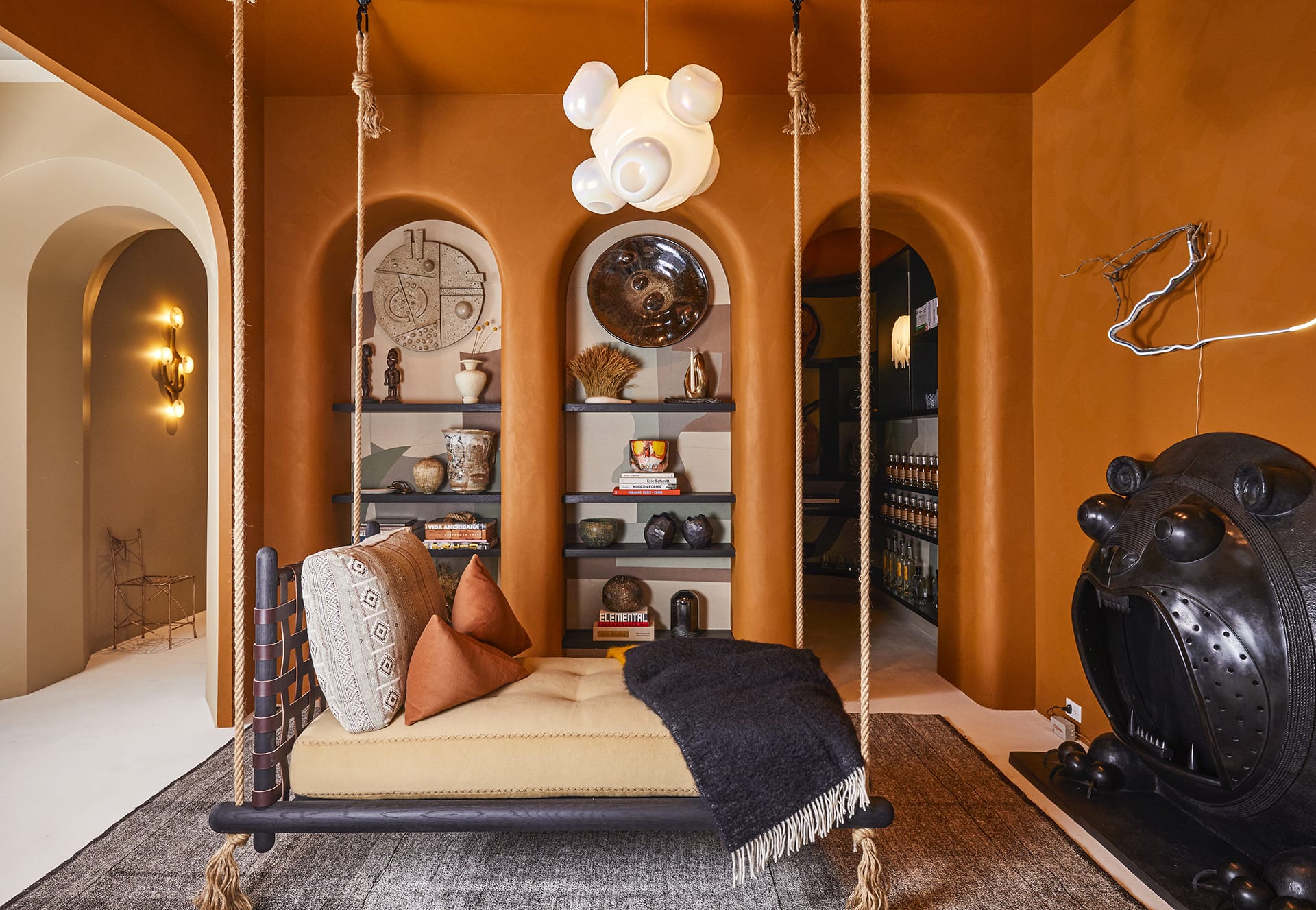 Modern room with a cozy swing, unique decor, shelves with books and ornaments, and a whimsical bear-shaped fireplace.