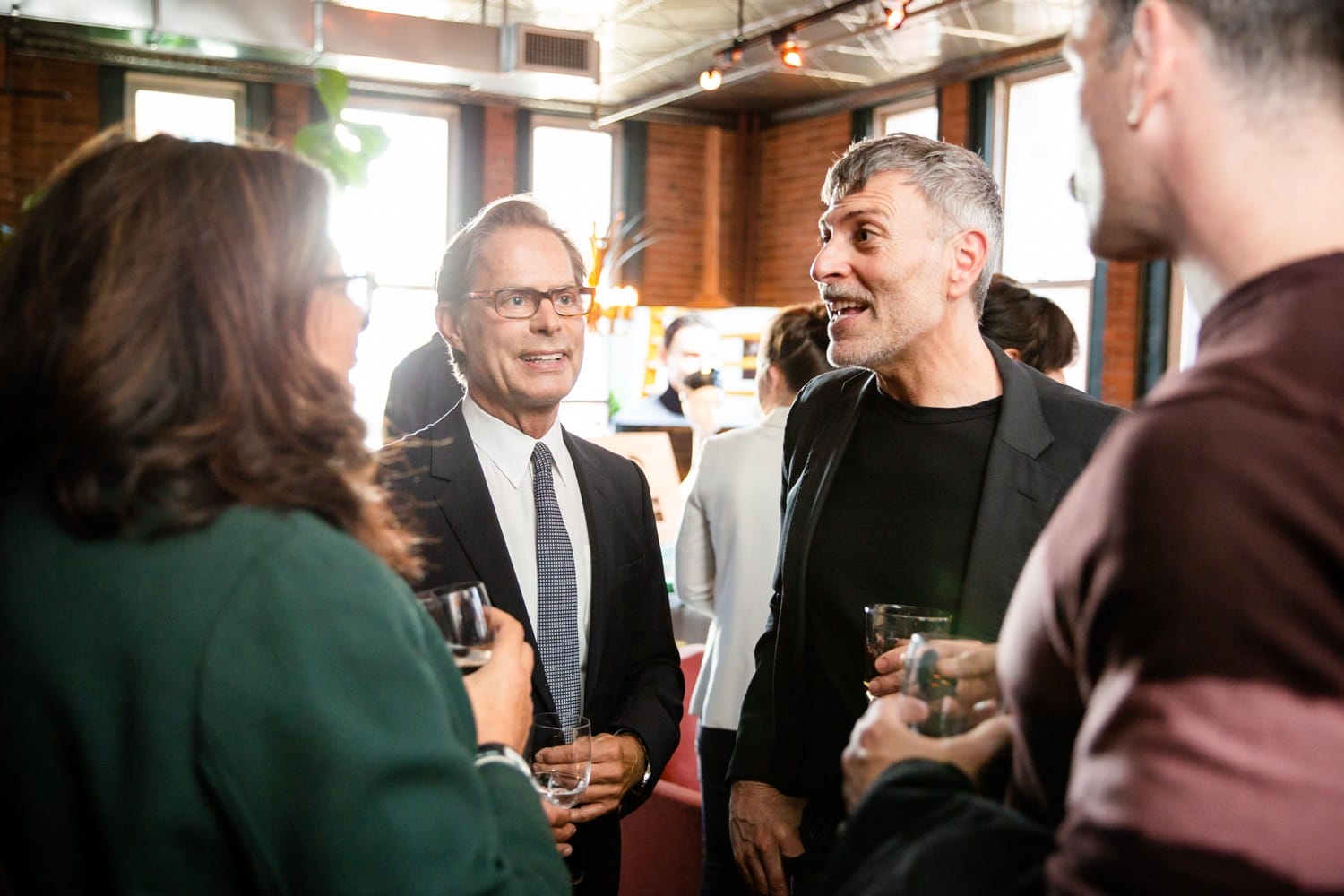Group of people socializing and holding drinks at a casual indoor gathering.
