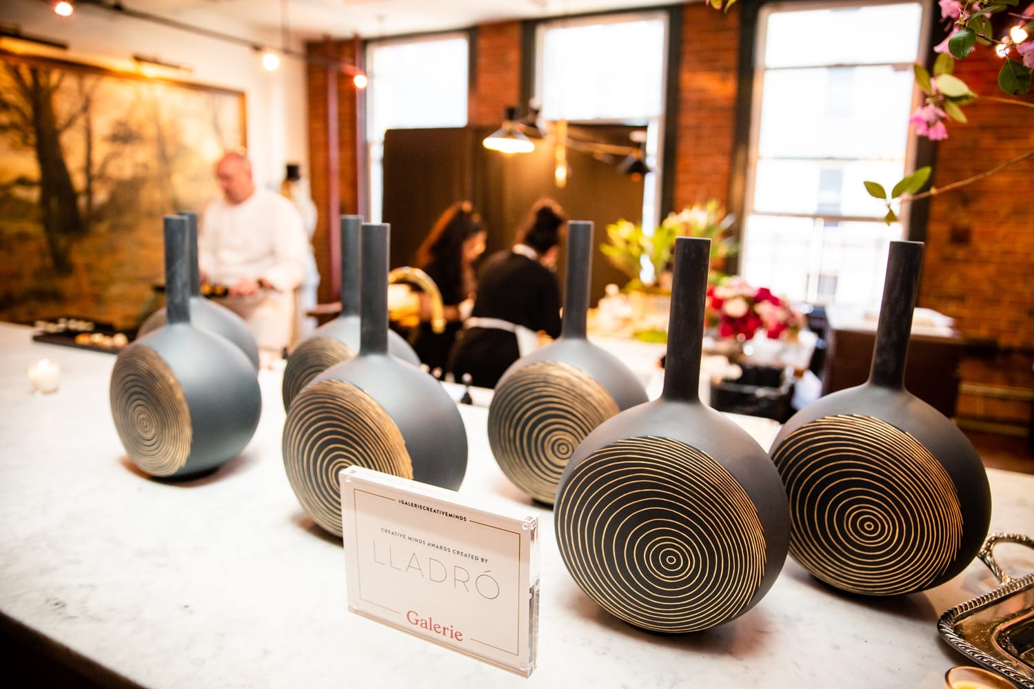 Display of decorative vases with intricate swirl patterns on a marble counter in a warmly lit room.
