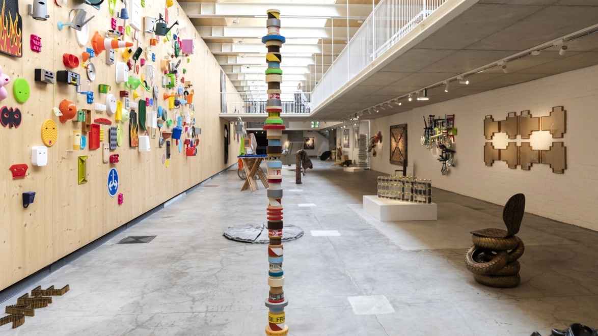 Contemporary art installation with colorful wall art and sculptures in a brightly lit modern gallery space.