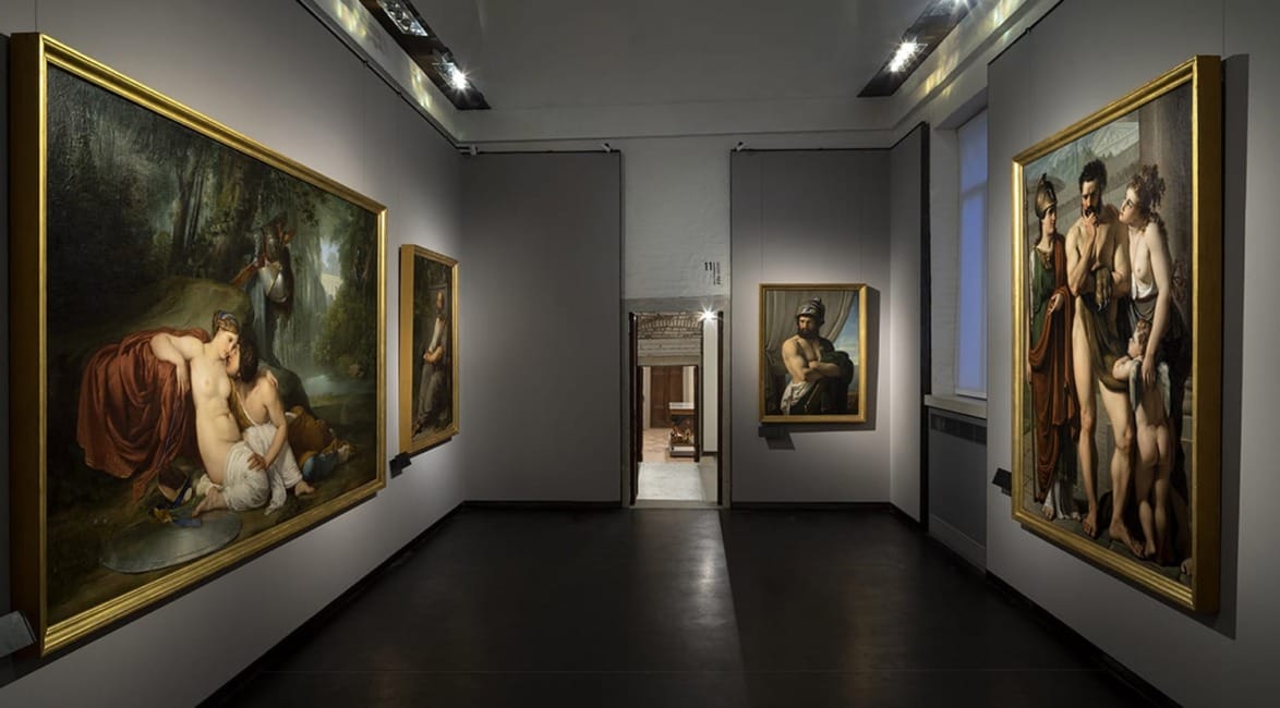 Art gallery interior with four large classical paintings on gray walls and soft lighting enhancing the artwork.