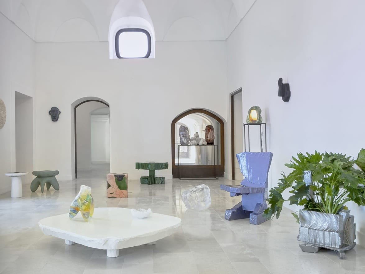 Art gallery interior with diverse, abstract sculptures in a bright room with arched doorways and minimalistic decor.
