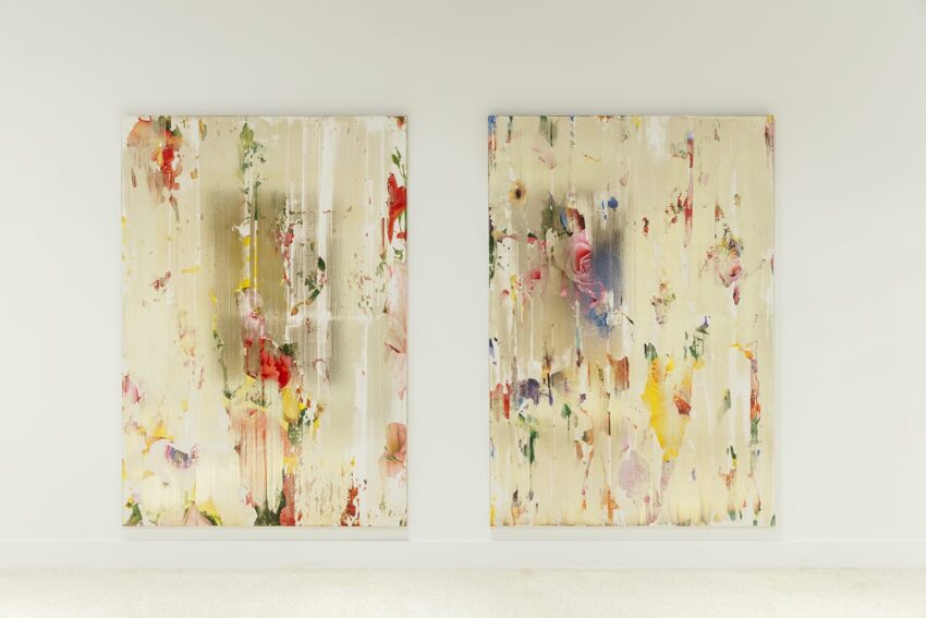 Two abstract paintings with vertical streaks and colorful splashes on a light-colored wall in a gallery setting.