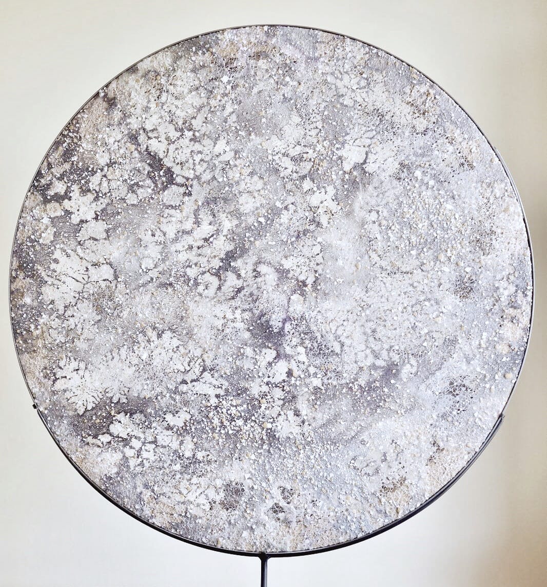 Round textured object on a stand, featuring a marbled gray and white pattern reminiscent of a lunar surface.
