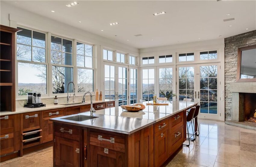 Spacious modern kitchen with large island, granite countertops, and floor-to-ceiling windows overlooking scenic outdoor view.
