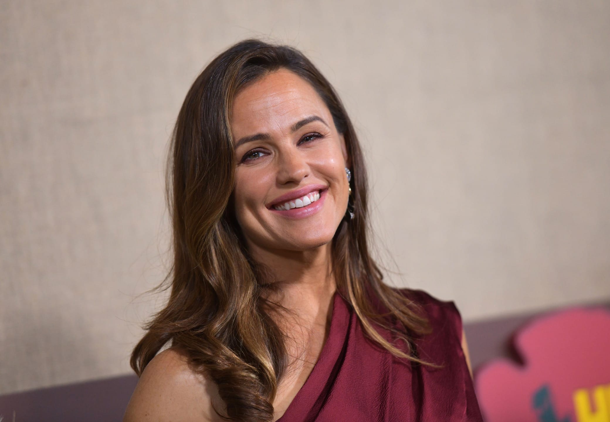 Person smiling in a maroon outfit with a neutral background.