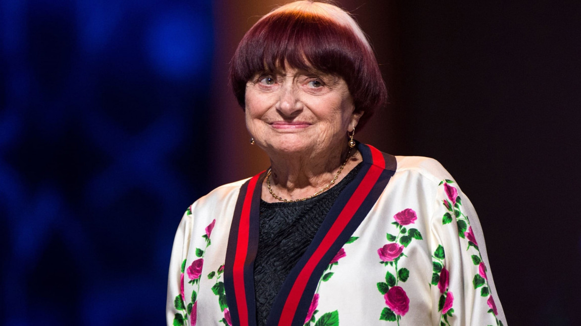 A woman with short hair wearing a floral-patterned jacket, standing in a warmly lit setting.