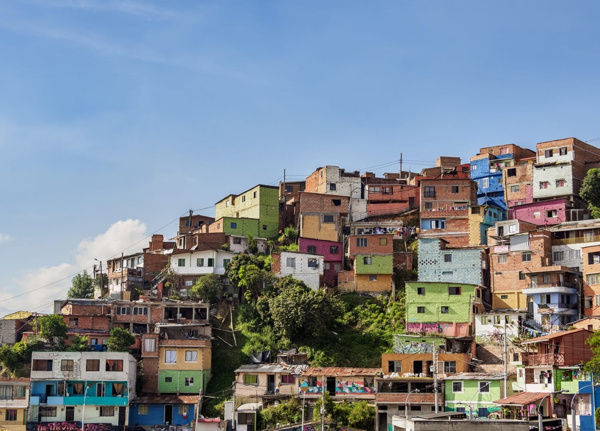 Colorful hillside houses in a vibrant neighborhood under a clear blue sky with scattered clouds.