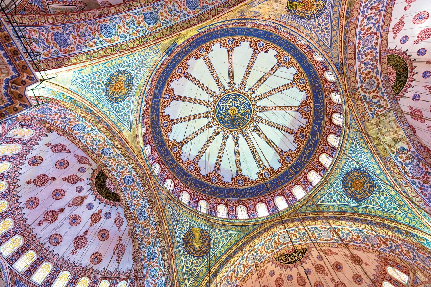 Ornate geometric design and intricate tile patterns on a domed mosque ceiling, showcasing Islamic art and architecture.