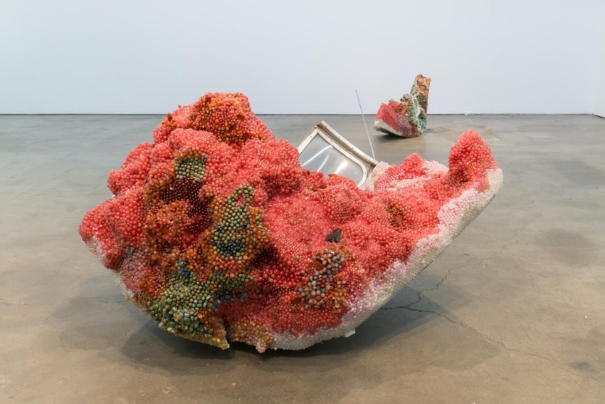 Colorful, abstract coral-like sculptures on concrete floor, incorporating small beads and metallic elements.