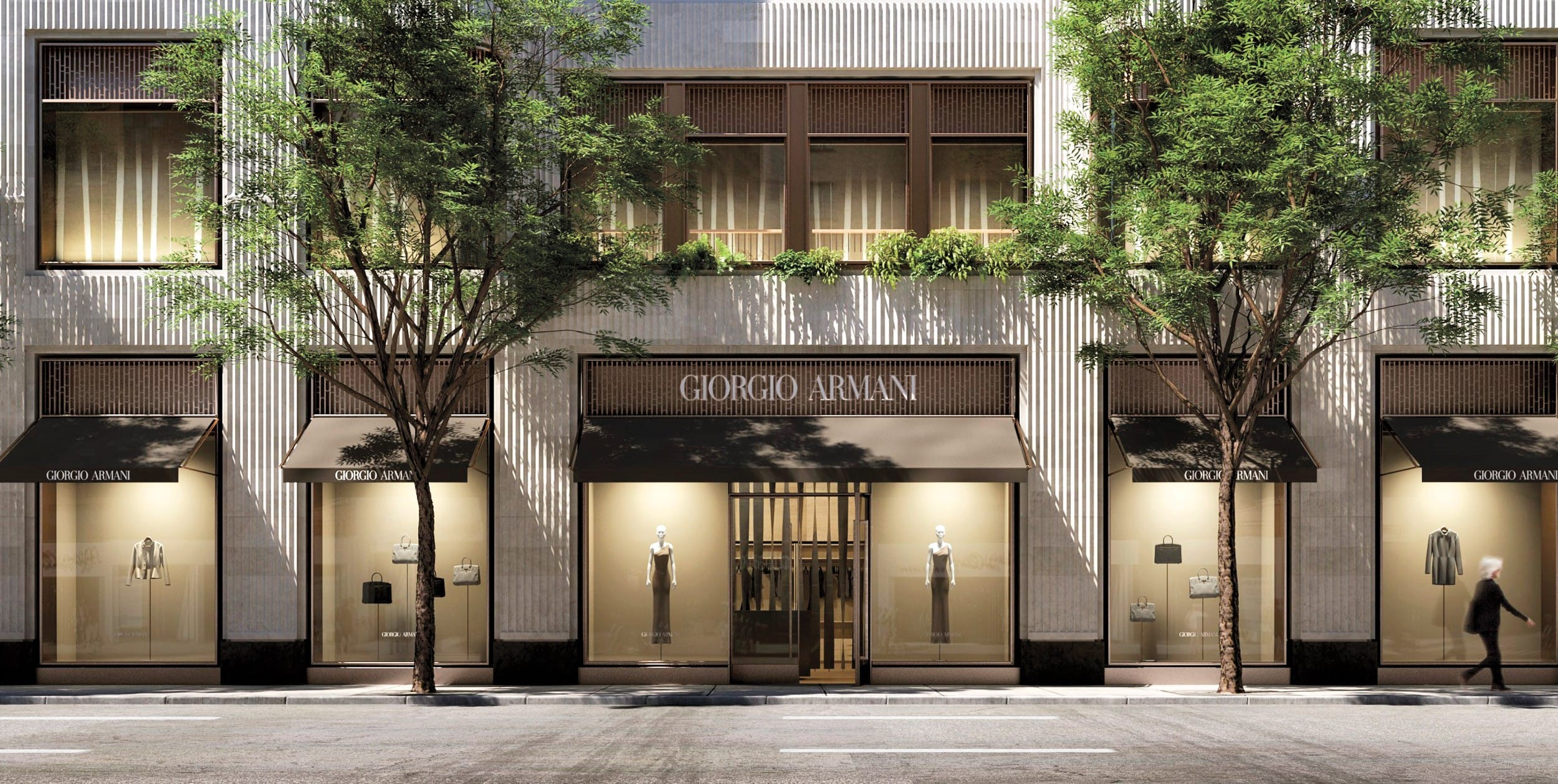 Front view of a Giorgio Armani store with large windows, trees lining the street, and a pedestrian walking by.