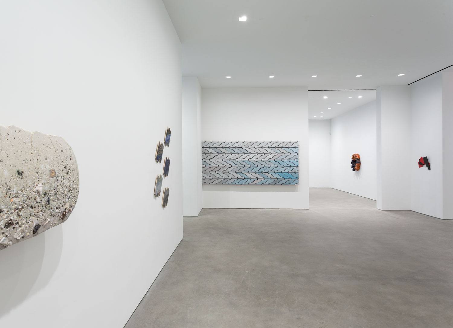 Contemporary art gallery with abstract sculptures and wall installations in a minimalist, bright white interior space.
