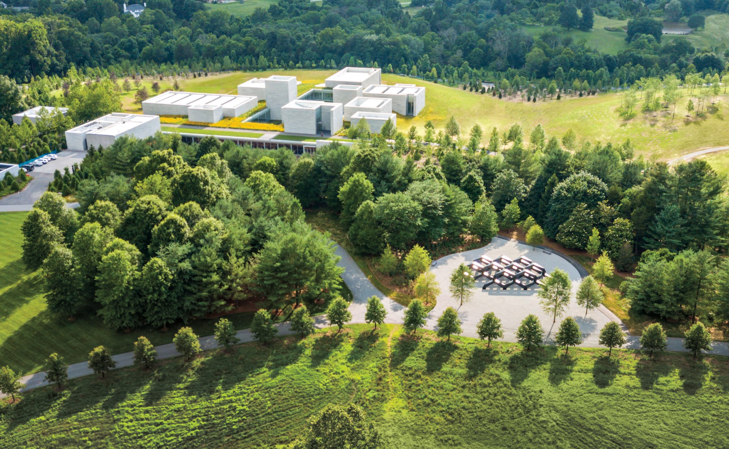 Aerial view of a modern architectural complex surrounded by lush green trees and landscape.