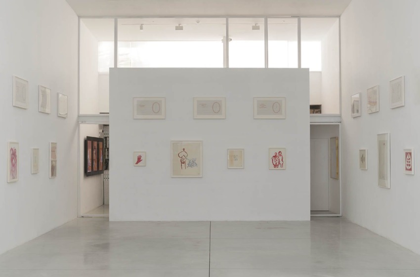 Art gallery room with framed abstract artworks on white walls, featuring various sizes and styles in a minimalist setting.