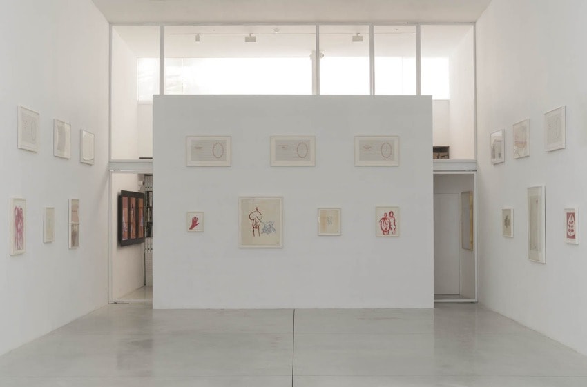 Art gallery room with framed abstract artworks on white walls, featuring various sizes and styles in a minimalist setting.