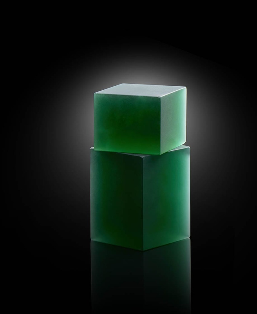 Two green translucent cubes stacked with a soft light reflection on a dark gradient background.