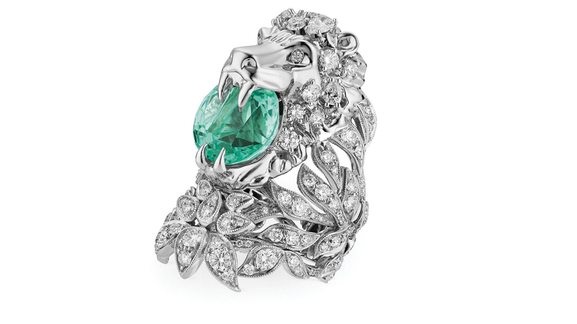 Lion-shaped silver ring with a large green gemstone and intricate leaf designs adorned with diamonds.