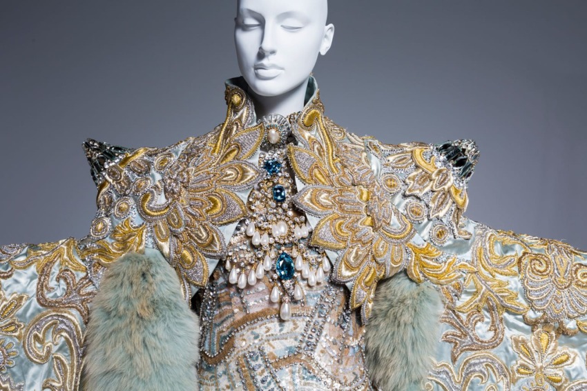 Intricately designed haute couture garment with elaborate embroidery, crystals, and luxurious fur accents on a mannequin.