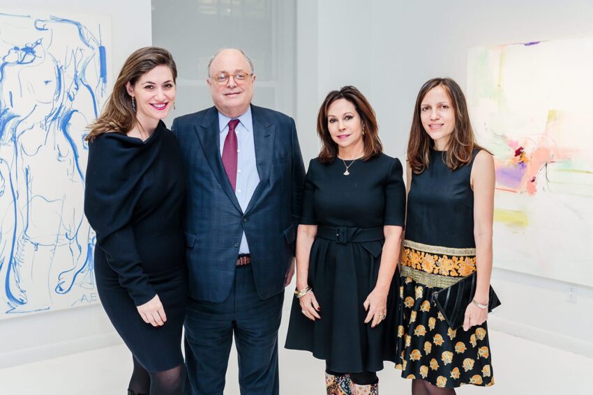 Four people standing in an art gallery with abstract paintings in the background.