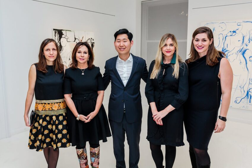 Five people standing together in an art gallery, smiling at the camera.