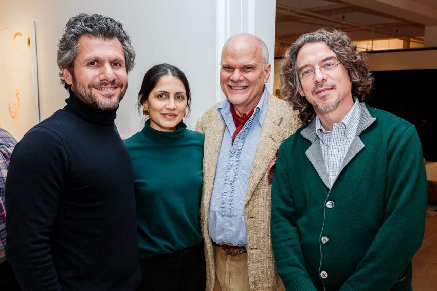 Group of four people smiling at an indoor event, dressed in casual and semi-formal clothing.