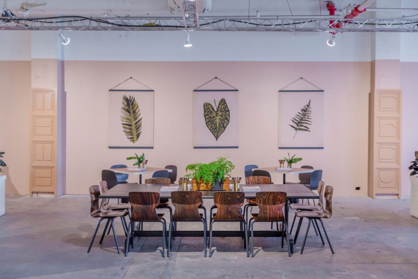 Large dining table in modern room with botanical wall art and plants.