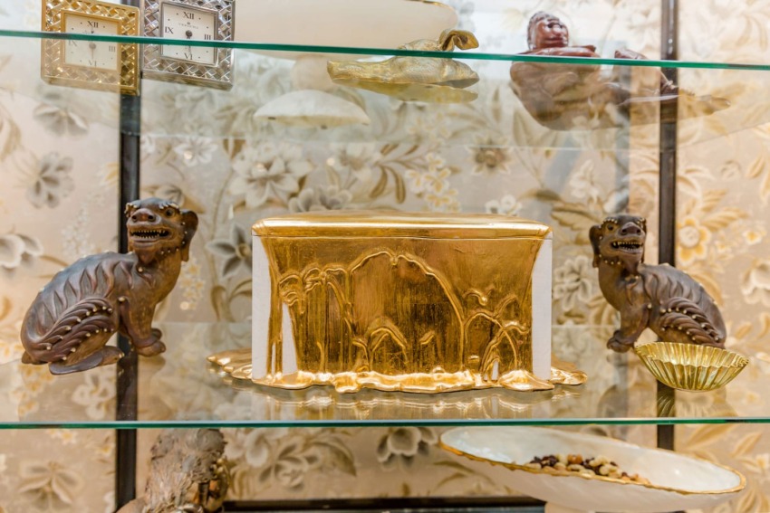 Decorative shelf with golden box centerpiece, surrounded by carved dragon figures and elegant bowls.