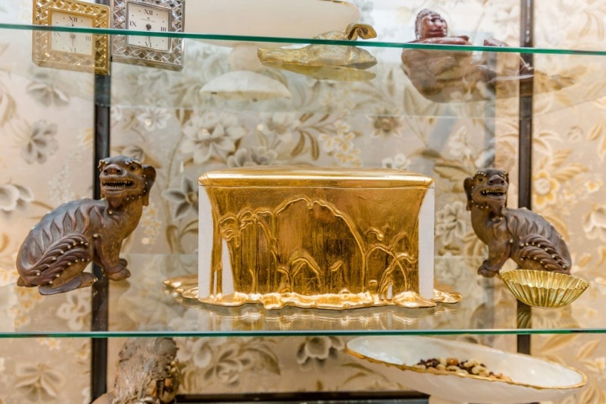Decorative shelf with golden box centerpiece, surrounded by carved dragon figures and elegant bowls.