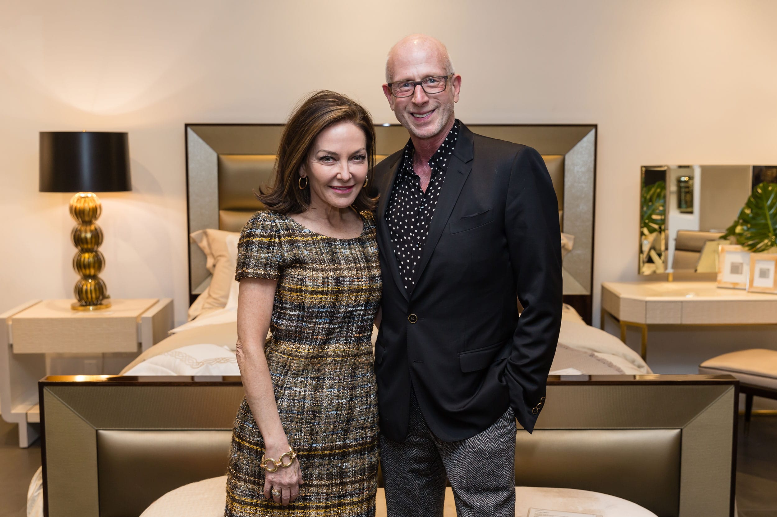 Two individuals standing in a modern bedroom showroom with stylish decor and lighting.