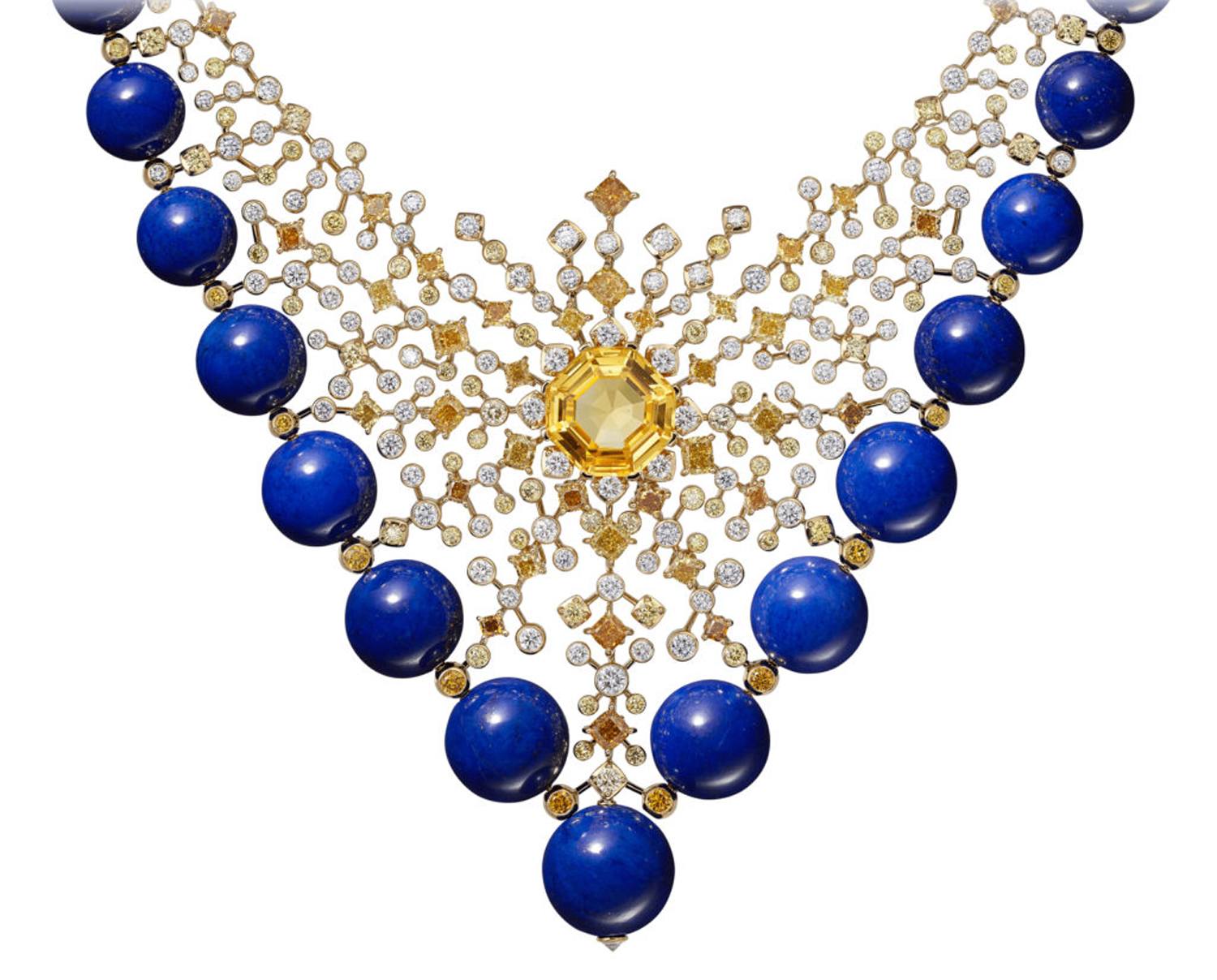 Intricate necklace with blue gemstones, gold details, and a central yellow gemstone arranged in a symmetrical design.