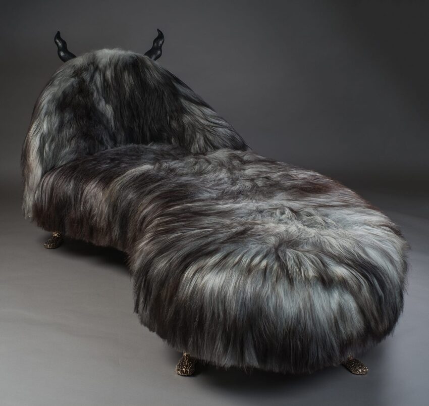 Furry chaise lounge with dark gray texture and horn-like accents, against a plain background.