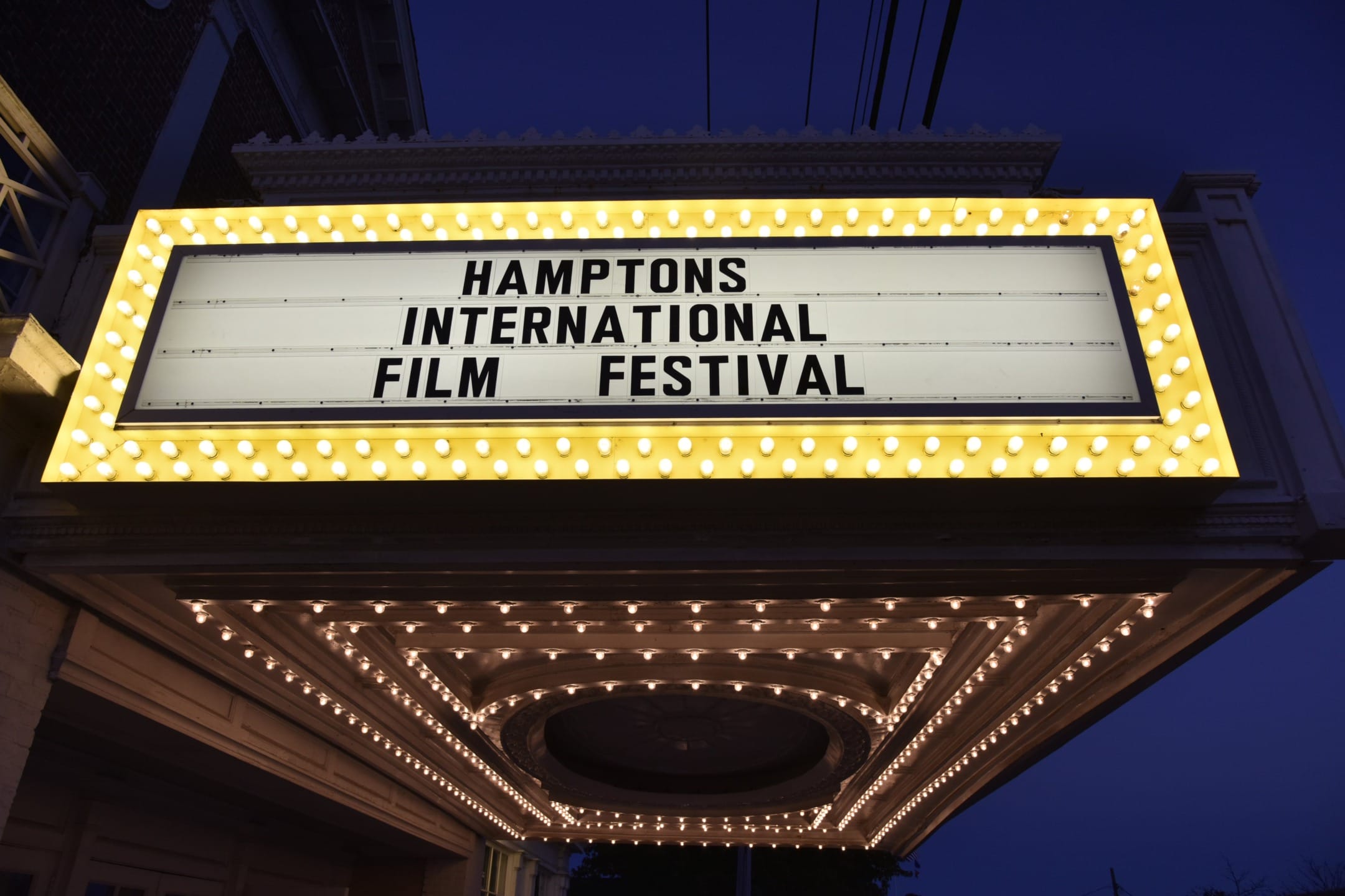 Marquee sign for Hamptons International Film Festival with lights glowing at dusk