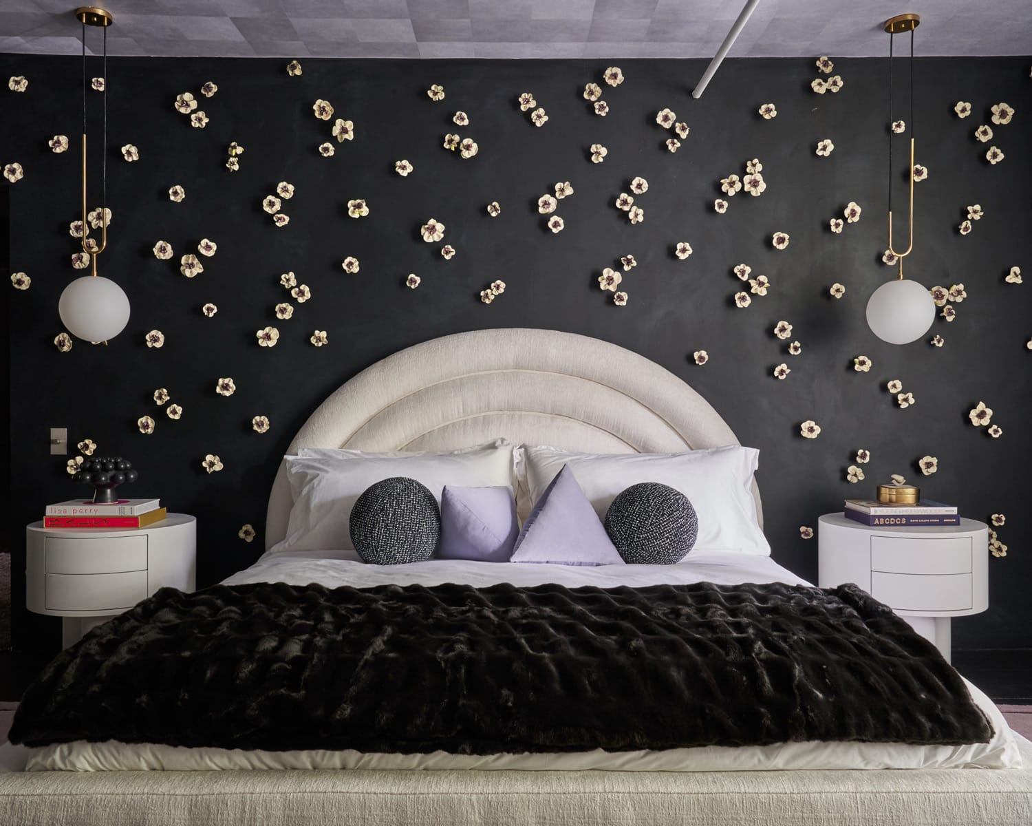 Modern bedroom with a black and flowered accent wall, round headboard, white bedding, and pendant lights.