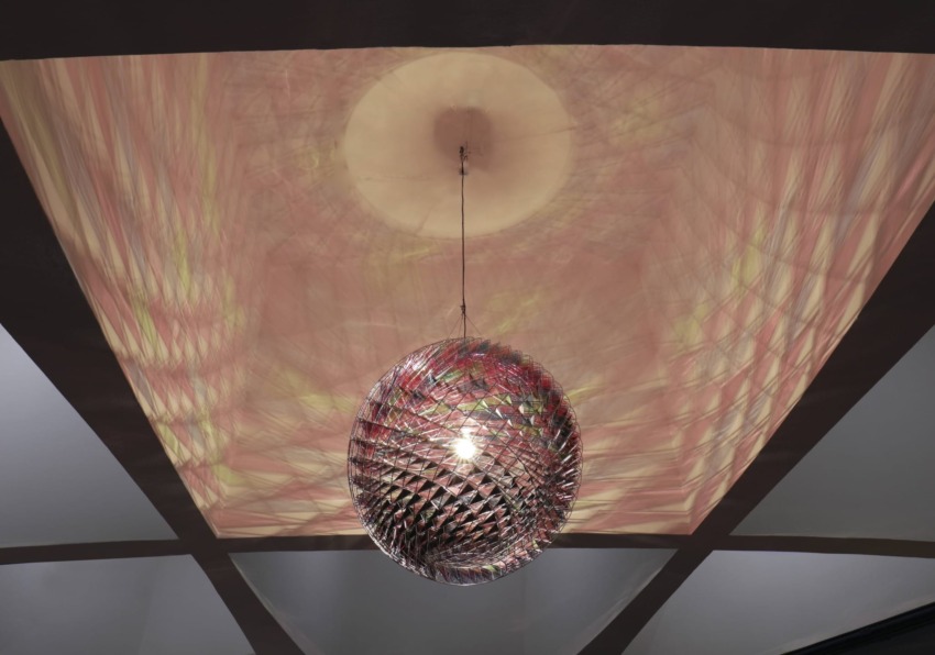 Colorful reflective sphere light fixture hanging from a ceiling with geometric patterns.