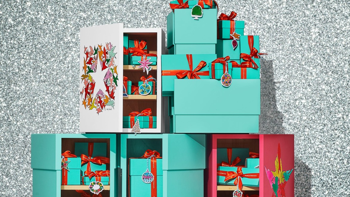 Gift boxes with red ribbons stacked against a glittery background.