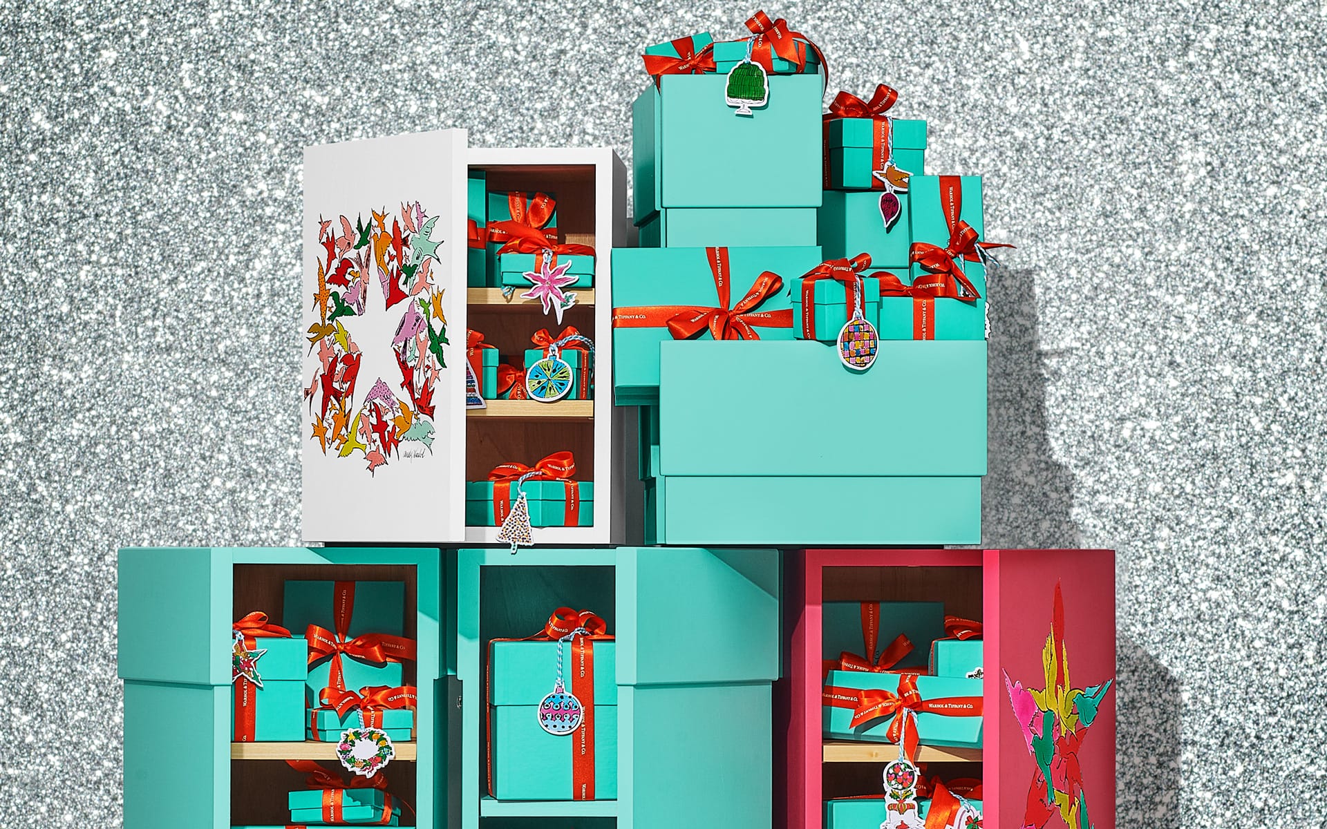 Gift boxes with red ribbons stacked against a glittery background.