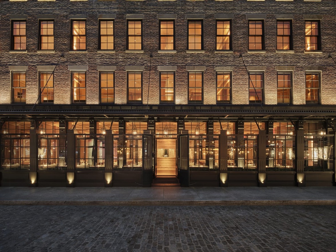Exterior view of a brick building with large windows illuminated from the inside, showcasing a warm and inviting atmosphere.