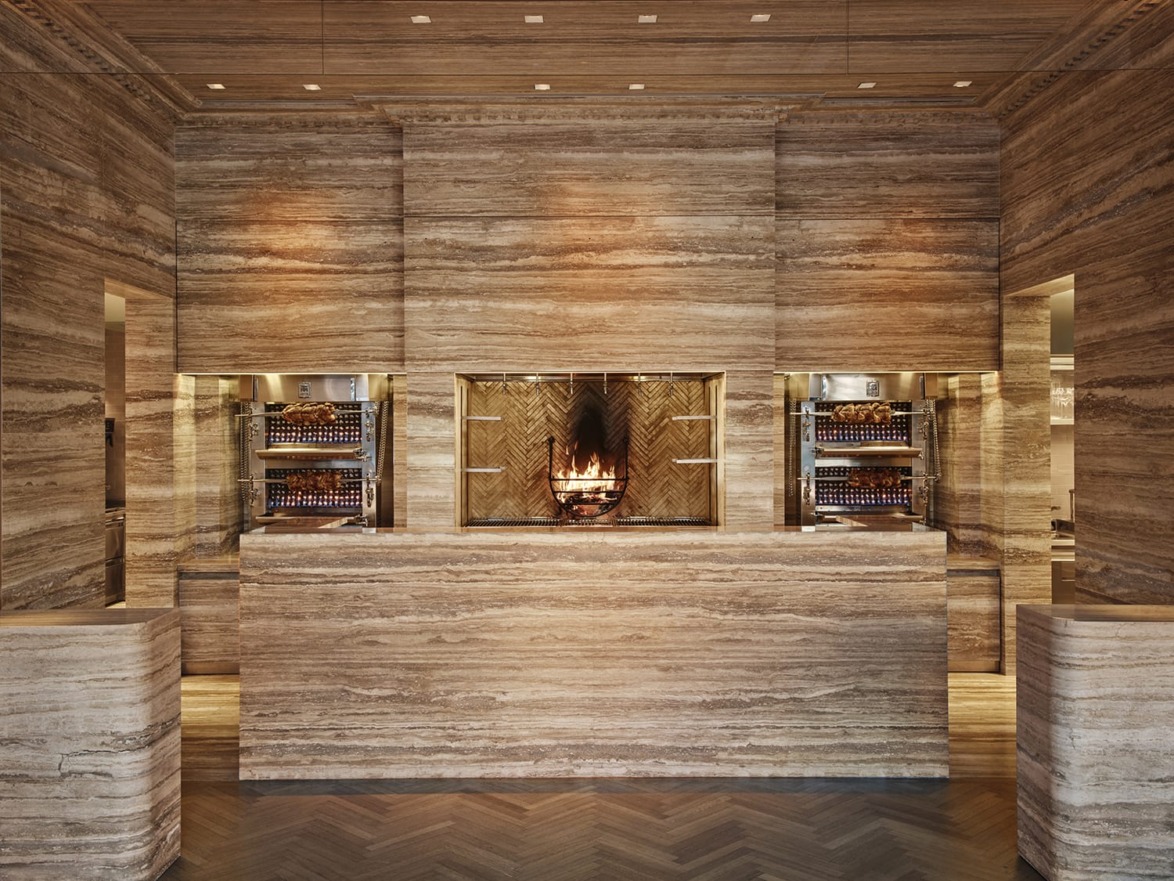 Elegant interior of a restaurant with warm lighting, wooden accents, and a central glass display featuring a decorative pattern.