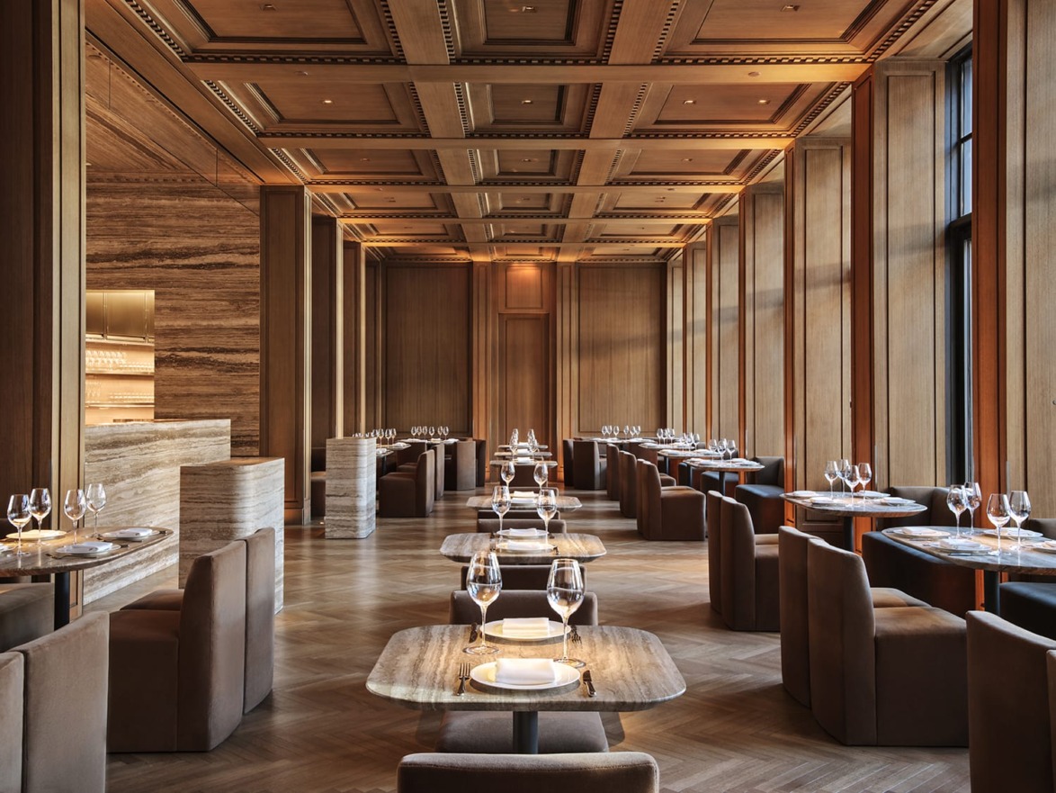 Luxurious restaurant interior with elegant wooden decor, set tables, and soft lighting creating a warm and inviting atmosphere.