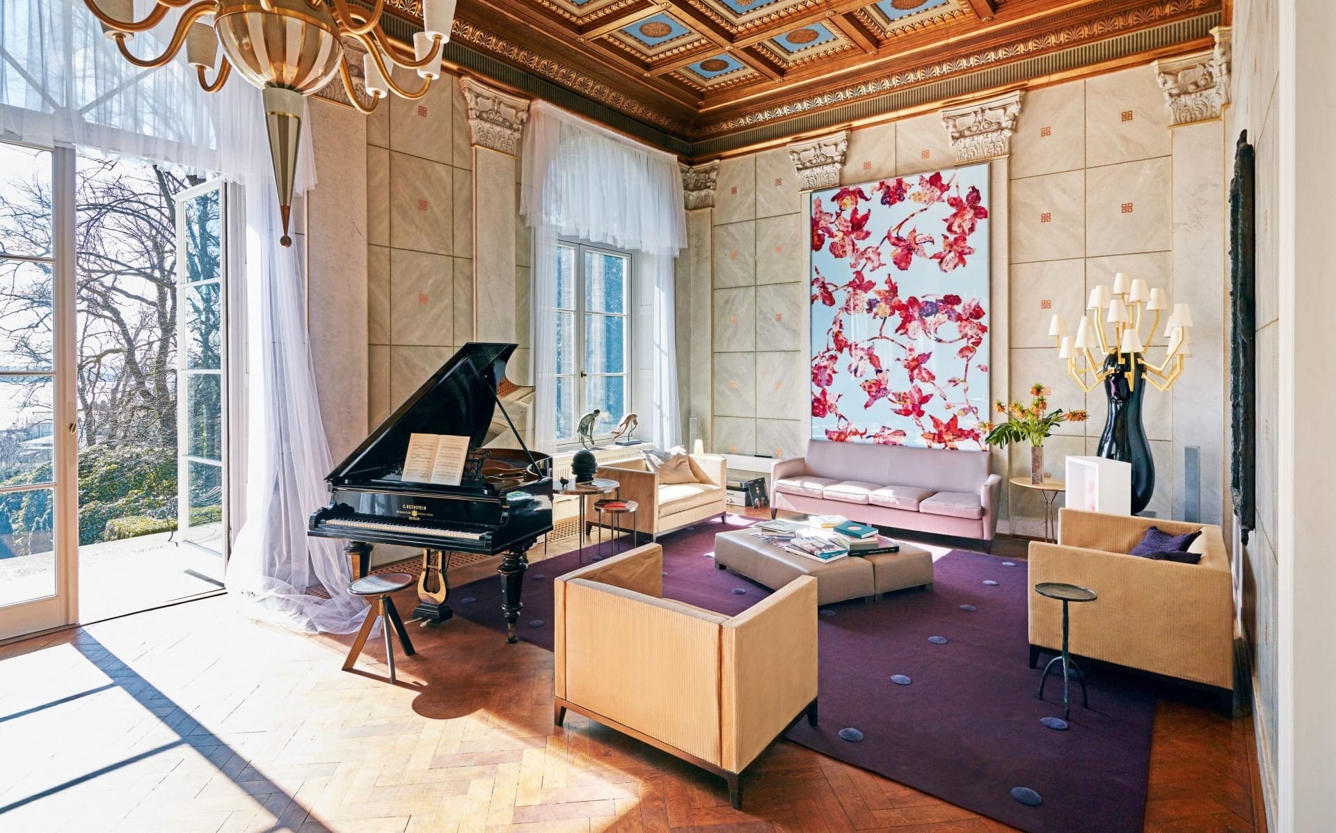 Elegant living room with grand piano, modern furniture, large windows, and a vibrant floral art piece on the wall.