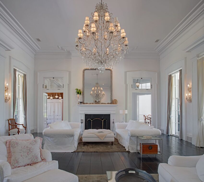 Elegant living room with a grand chandelier, white sofas, and a fireplace, creating a sophisticated and cozy ambiance.