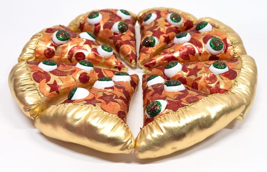 Plush toy pizza with gold crust and whimsical toppings like green, white, and red shapes, arranged in a full circle.