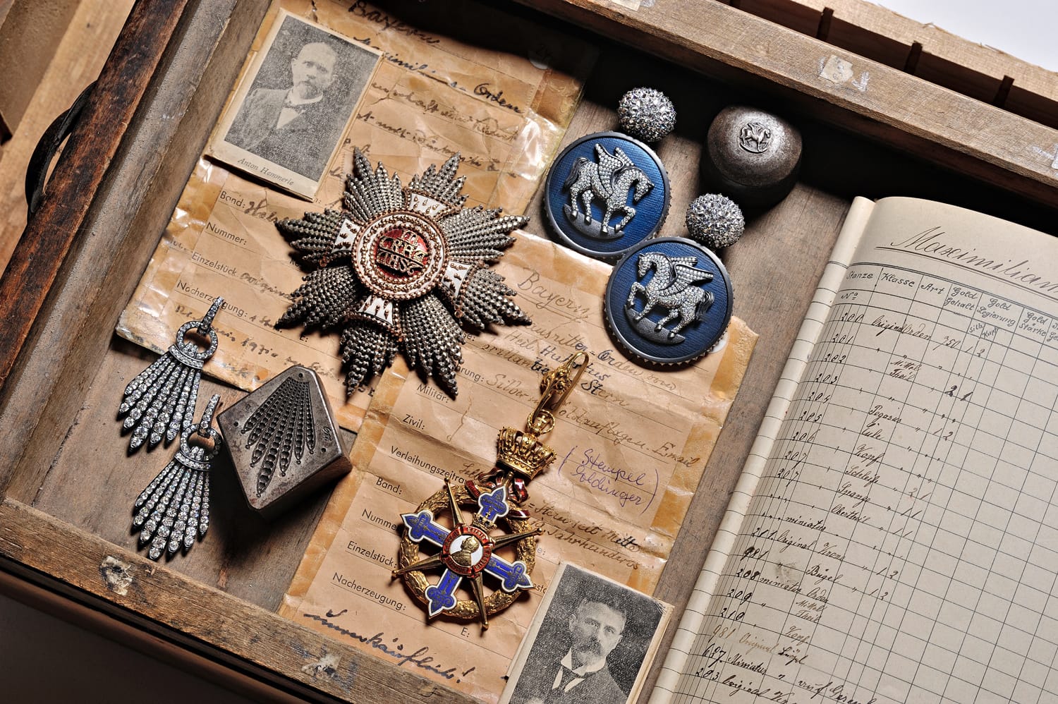 Box with vintage medals, photographs, and documents, showcasing military and historical memorabilia arranged neatly.