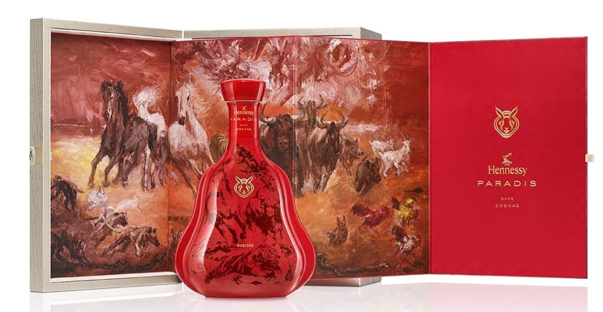 Red Hennessy Paradis bottle with intricate artwork displayed inside an open red and brown box with painted animals.